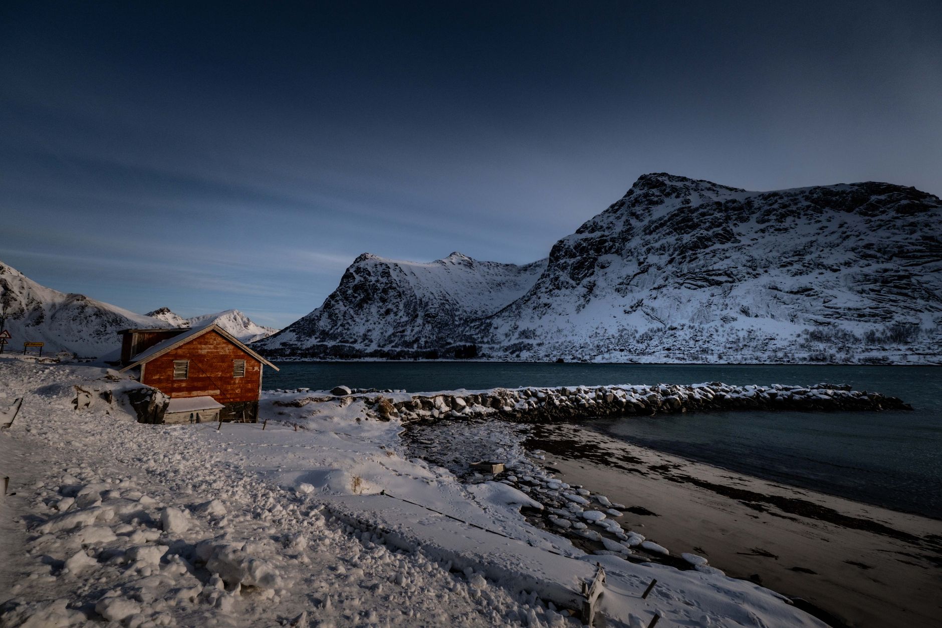Minimalist timber cabin over misty Norwegian fjord waters